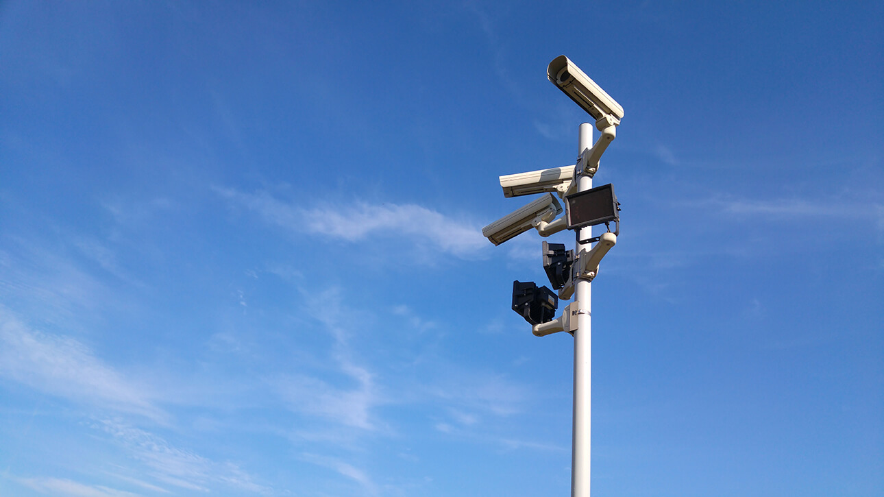 CCTV cameras on a pole against a blue sky