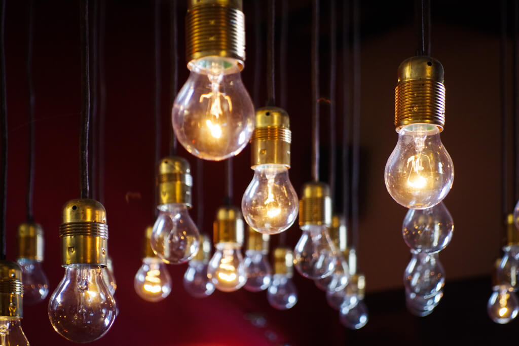 Rows of bare filament bulbs hanging from brass holders