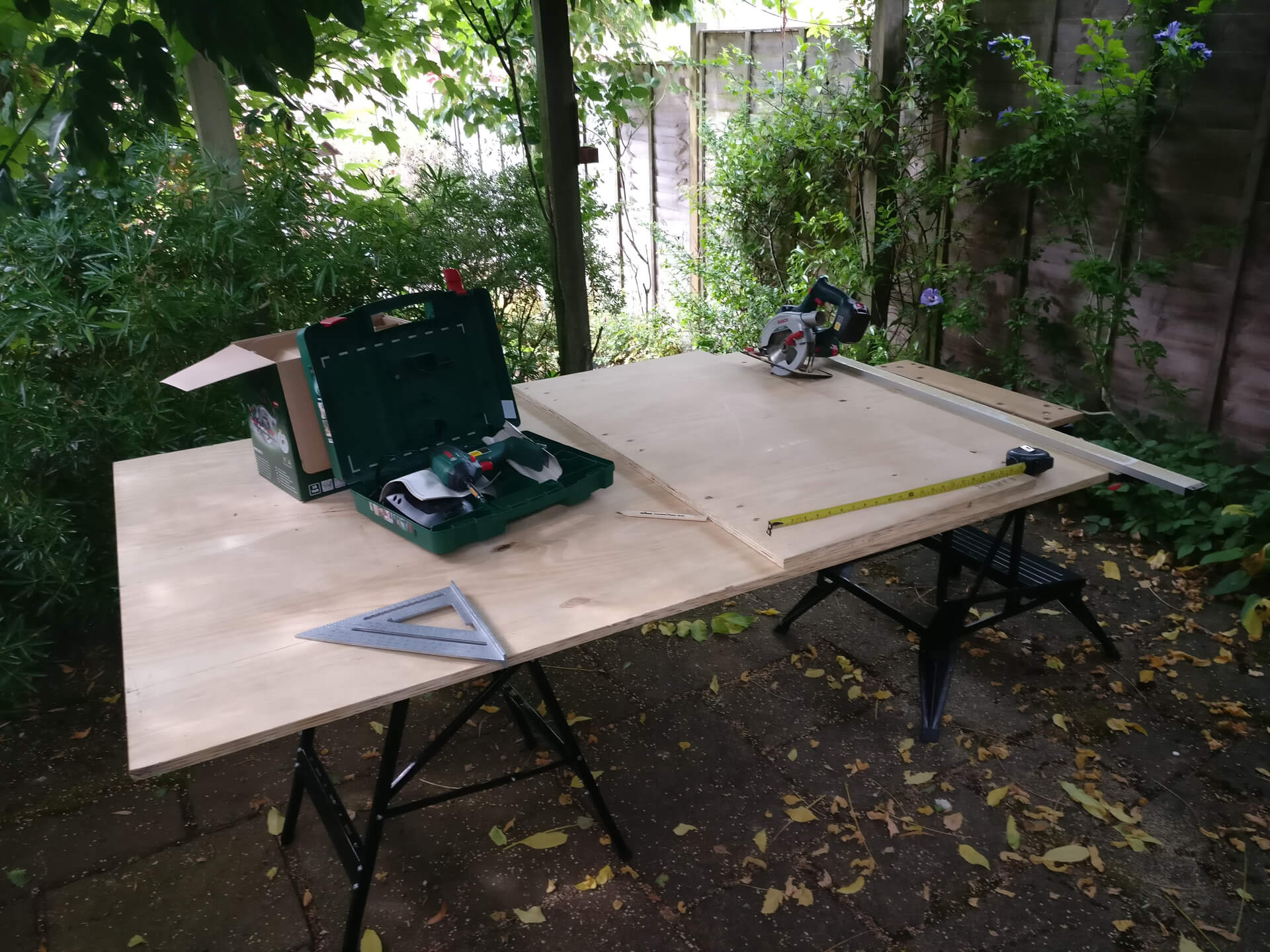 A sheet of plywood across two folding workbenches, ready to cut with the circular saw