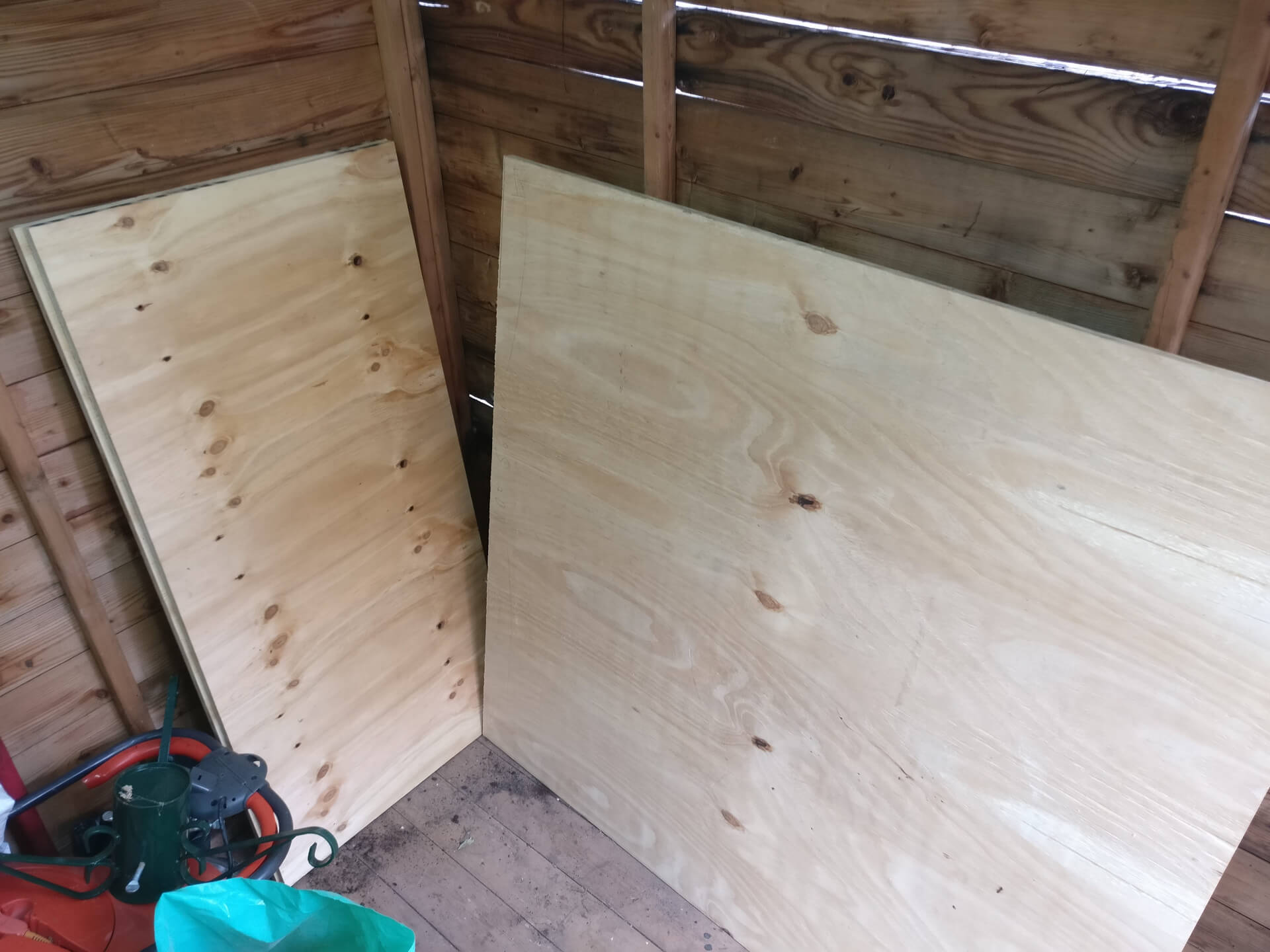 The cut plywood pieces leaning against the shed wall