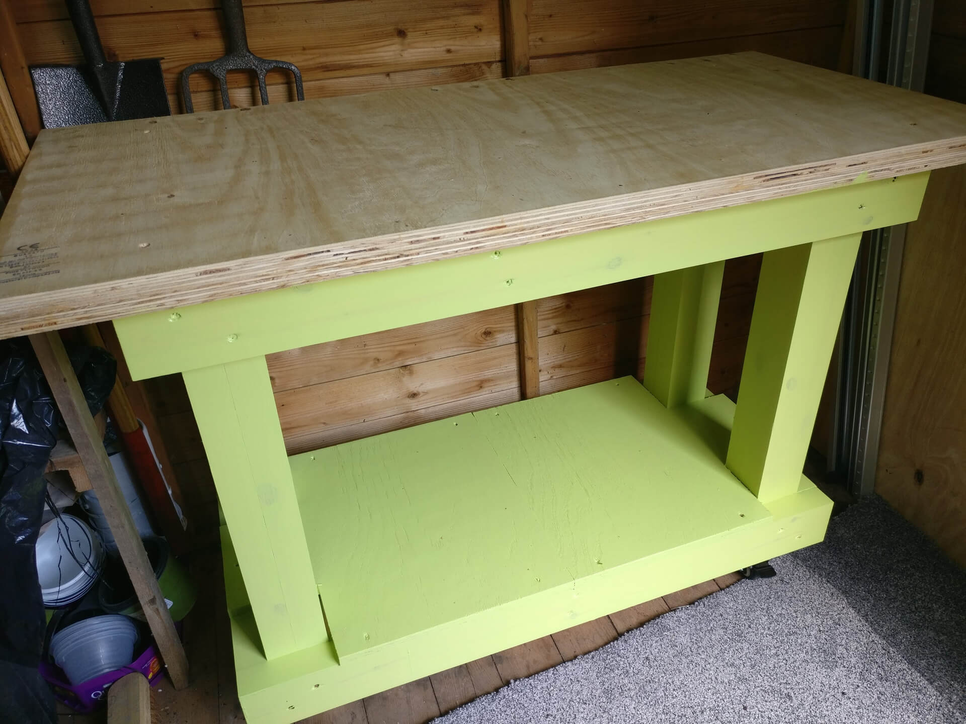The finished workbench, painted lime green with a plywood top, in the shed