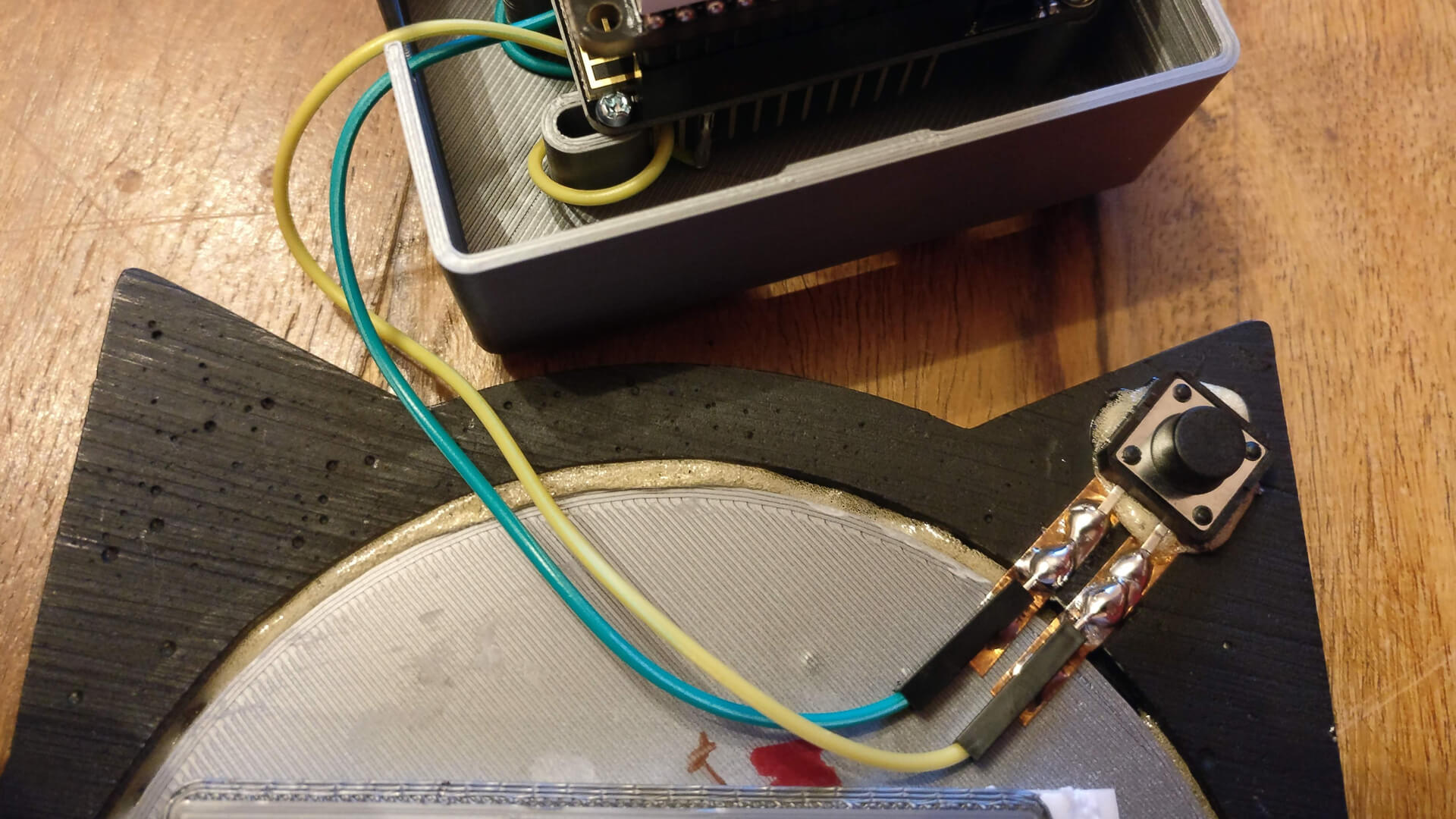 The push button stuck behind the left ear and wired with copper tape