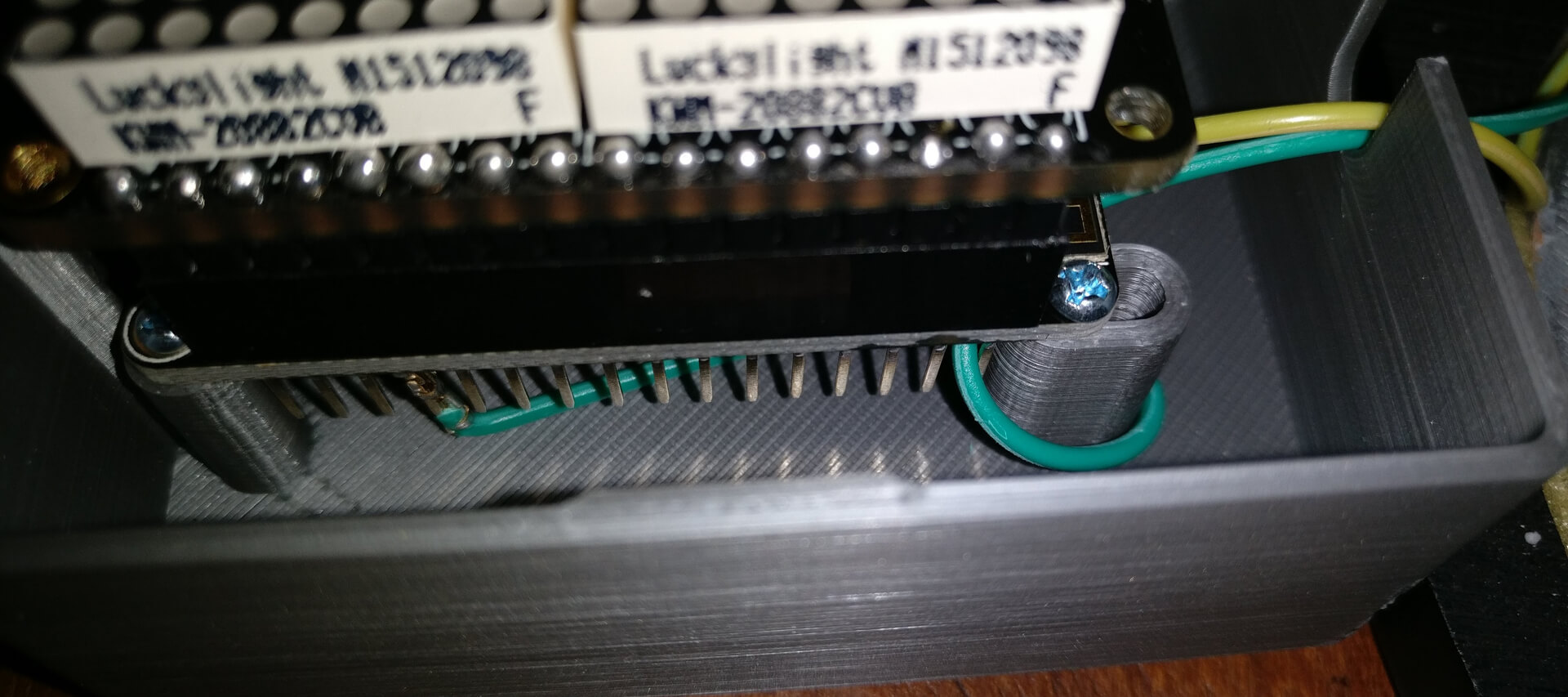 Jumper wires plugged into the Feather's header pins inside its case