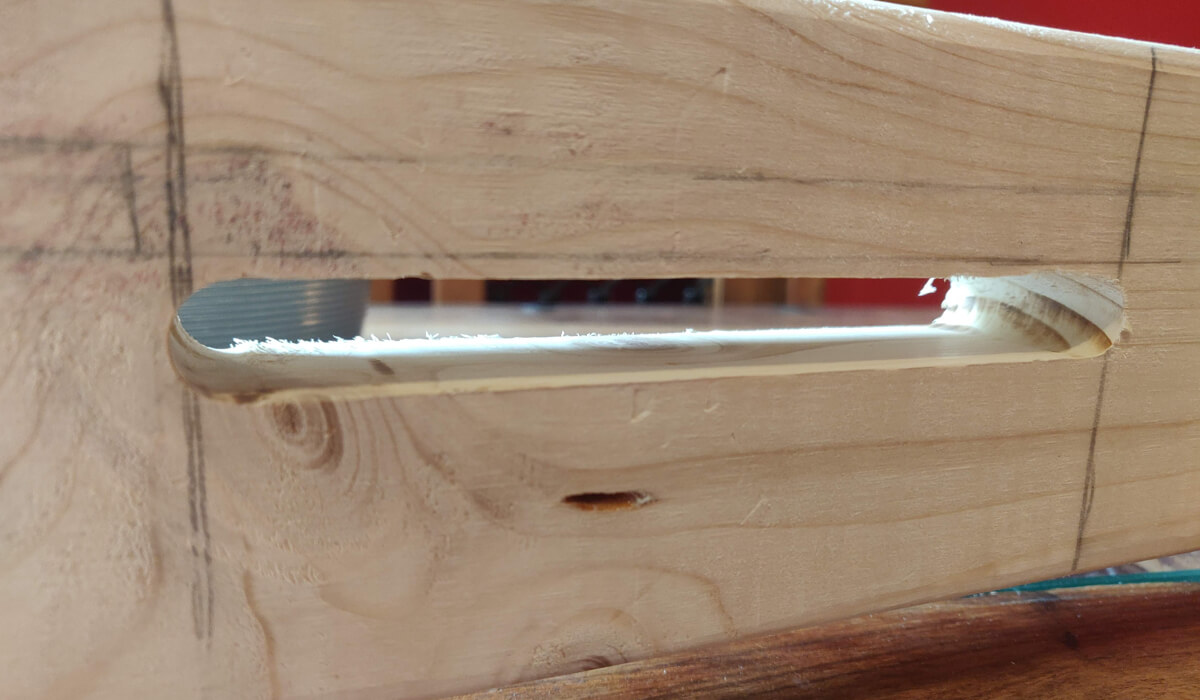 The slot routed through the loom's upright for the tension rod
