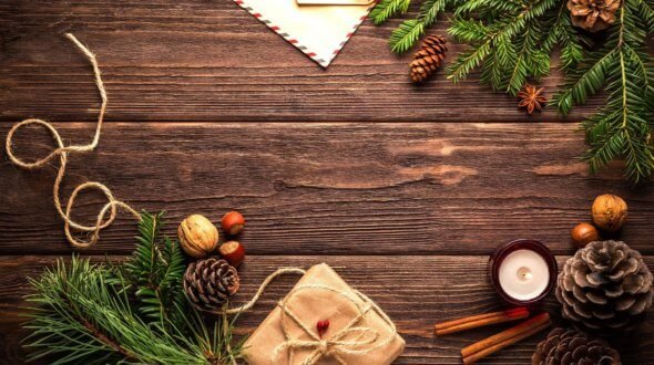 Pine cones, fir branches, walnuts and a string-tied gift on a dark wooden table