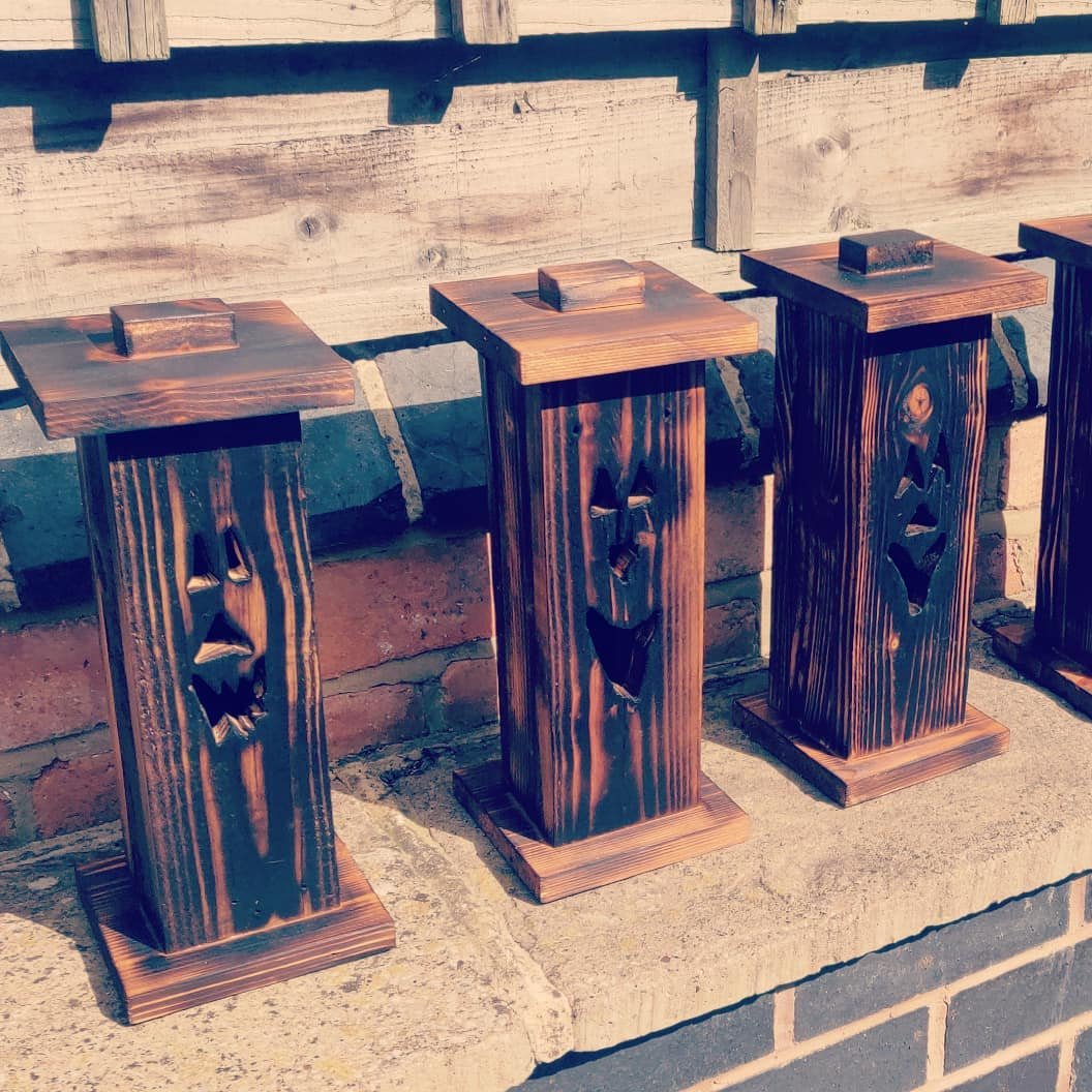 Three of the lanterns in the sun on a garden wall, each with a different cut-out face
