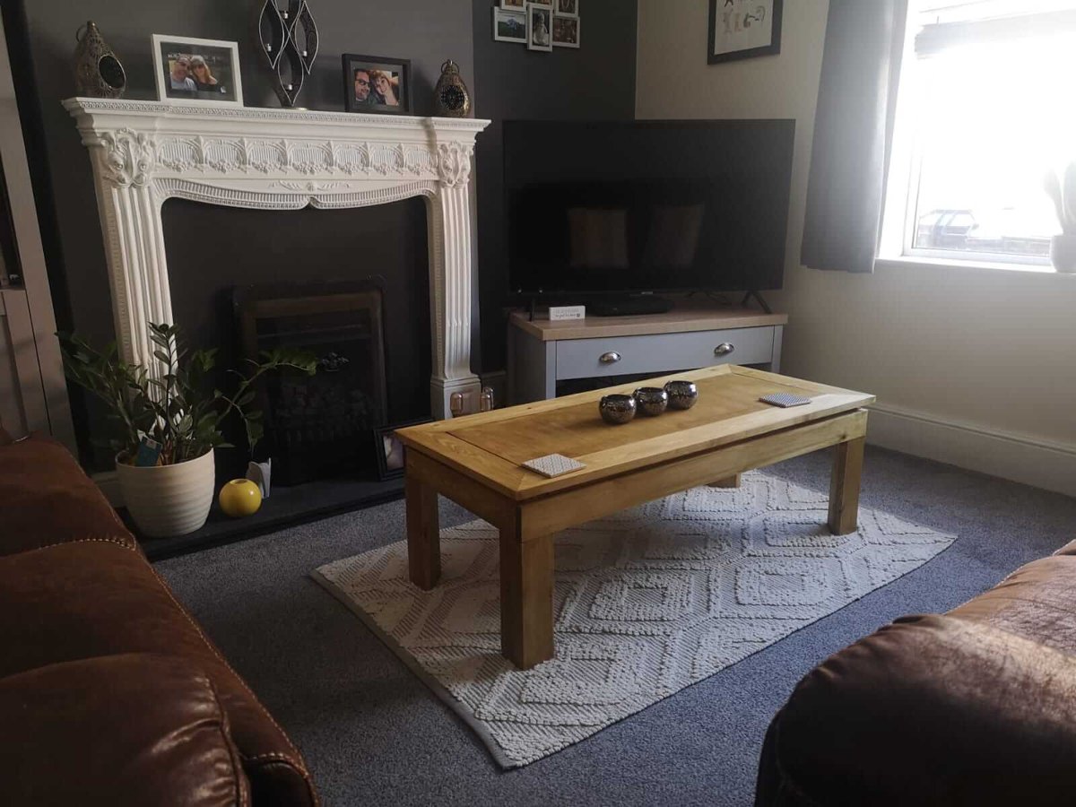 The coffee table from the doorway, between a leather sofa and the television